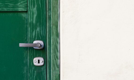 green wooden door beside white wall